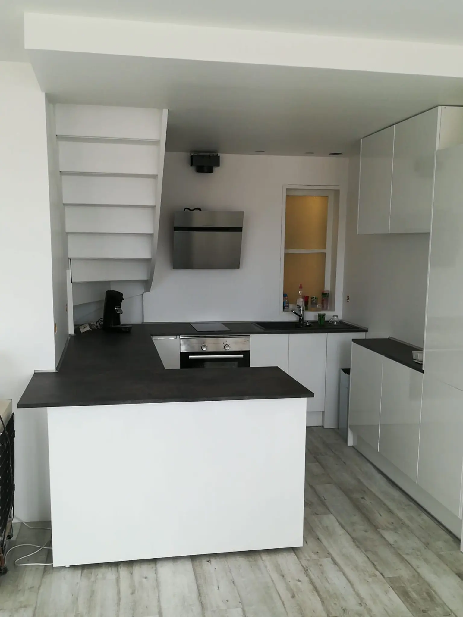 Espace après rénovation avec cuisine blanche aménagée, plafond fini et rangements intégrés