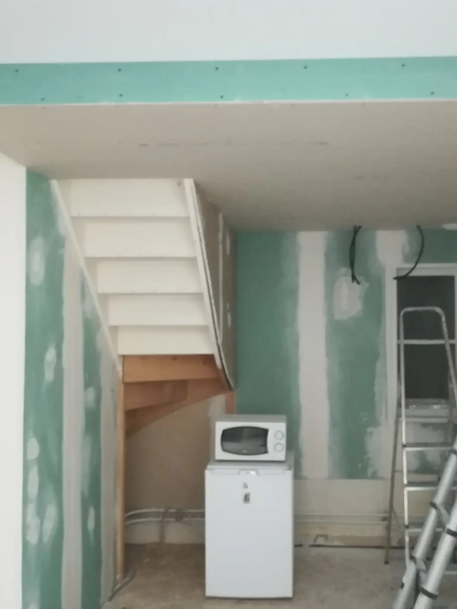 Espace cuisine avant rénovation avec cloisons en plaques de plâtre et plafond en cours de préparation